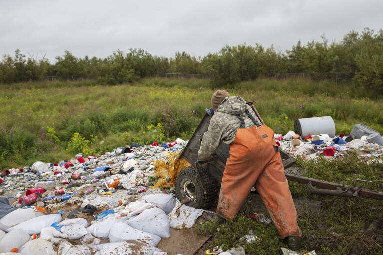 Joseph Moses empties a honey bucket at the village landfill site, Friday, Aug. 18, 2023, in Akiachak, Alaska. (AP Photo/Tom Brenner)