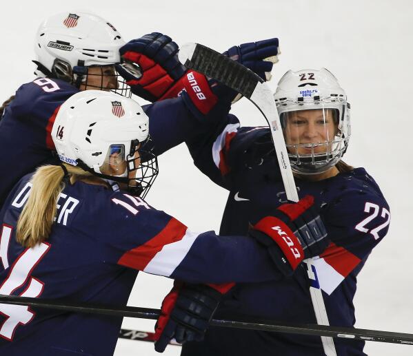 FILE - In this Feb. 17, 2014, file photo, Kacey Bellamy of the United States, right, is congratulated by teammates after scoring a goal against Sweden during the first period of the 2014 Winter Olympics women's semifinal ice hockey game in Sochi, Russia. Three-time U.S. Olympian Kacey Bellamy is retiring a month after the women's world hockey championships were postponed. Bellamy, who turned 34 in April, announced her decision Tuesday, May 18, 2021, to retire after 15 years with the U.S. women's national team.(AP Photo/Julio Cortez, File)