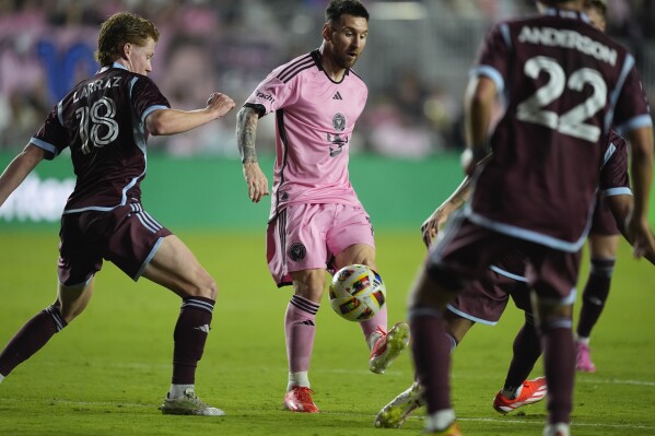 Inter Miami forward Lionel Messi, center, kickss the ball past Colorado Rapids midfielder Oliver Larraz (18) during the second half of an MLS soccer match, Saturday, April 6, 2024, in Fort Lauderdale, Fla. (AP Photo/Rebecca Blackwell)