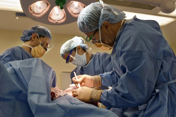 Surgeons perform a bilateral mastectomy on a transgender patient at a hospital in Boston on Friday, July 15, 2016. The number of gender-affirming surgeries in the U.S. nearly tripled from 2016 to 2019 before declining slightly in 2020 when about 12,800 procedures were done, according to a study published Wednesday, Aug. 23, 2023, in JAMA Network Open. (Christine Hochkeppel/Worcester Telegram & Gazette via AP)