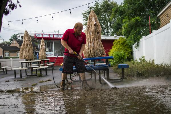 A worker cleans the outside area of Four Boys Ice Cream store during the passing of Tropical Storm Henri in Jamesburg, N.J., Monday, Aug. 23, 2021. (AP Photo/Eduardo Munoz Alvarez)