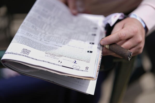 A race fan looks at a program at Churchill Downs before the 151st running of the Kentucky Oaks horse race Friday, May 2, 2025, in Louisville, Ky. (AP Photo/Brynn Anderson)