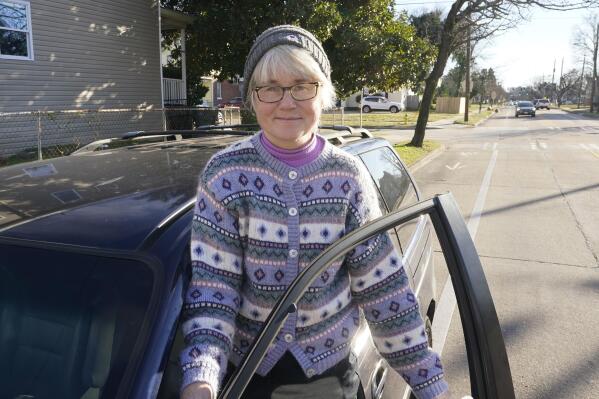 Norfolk resident Kim Williams poses with her van that got stuck on flooded roadway near her house several years ago Wednesday Jan. 19, 2022, in Norfolk, Va. An Australian tech firm has partnered with the Waze traffic app and the city of Norfolk to warn residents of flooded roadways in real time. (AP Photo/Steve Helber)