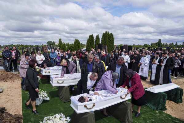 Relatives say goodbye to children Roman Martyniuk, 17, Tamara Martyniuk, 8, and Stanislav Martyniuk, 12, killed in a Russian strike on Sunday, during farewell ceremony in Korostyshiv, Zhytomyr region, Ukraine, Wednesday, May 28, 2025. (AP Photo/Evgeniy Maloletka)