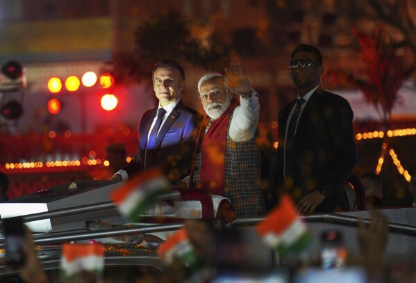 French President Emmanuel Macron, left, and Indian Prime Minister Narendra Modi, with his arm outstretched, ride an open vehicle together during a road show in Jaipur, Rajasthan, India, Thursday, Jan. 25, 2024. Macron will be the chief guest at India's annual republic day parade in New Delhi on Friday. (AP Photo/ Deepak Sharma)