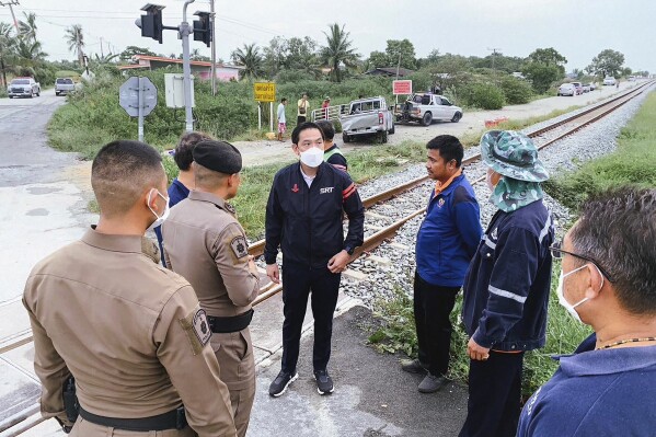 In this photo released by public relations of the State Railway of Thailand, Gov. of the State Railway of Thailand Nirut Maneepan, fourth form left, talks to police at a crash site in Muang, Chachoengsao province, Thailand, Friday, Aug. 4, 2023. Several people were killed when a freight train struck a pickup truck, seen rear left, crossing the tracks in an eastern province of Thailand early Friday morning, authorities said. (Public relations of the State Railway of Thailand via AP )