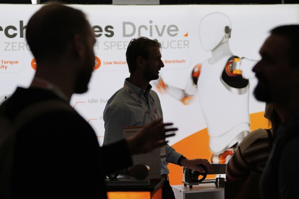 Casper van Eersel, center, a representative of IMSystems, a Netherlands-based company which makes robot components, talks with convention guests at the Robotics Summit & Expo, Wednesday, April 30, 2025, in Boston. (AP Photo/Charles Krupa)