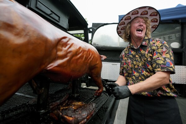 Brad Orrison, of The Shed BBQ and Blues Joint team, laughs as a whole hog is pulled from his cooker at the World Championship Barbecue Cooking Contest, Saturday, May 18, 2024, in Memphis, Tenn. (AP Photo/George Walker IV)