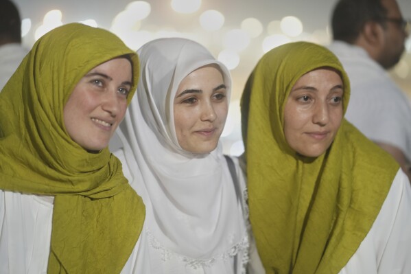 Muslim pilgrims pose for a photo on the rocky hill known as the Mountain of Mercy on the Plain of Arafat during the annual Hajj pilgrimage near the holy city of Mecca, Saudi Arabia, Thursday, June 5, 2025. (AP Photo/Amr Nabil)
