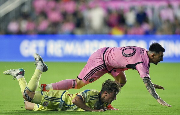 Inter Miami forward Lionel Messi falls on New York Red Bulls midfielder Daniel Edelman during the first half of an MLS soccer game, Saturday, May 4, 2024, in Fort Lauderdale, Fla. (AP Photo/Michael Laughlin)