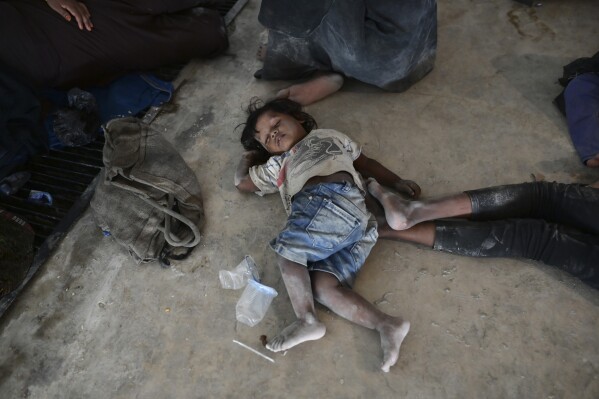 A Rohingya child takes a nap on the floor in the basement of a building that is turned into a temporary shelter in Banda Aceh, Aceh province, Indonesia, Tuesday, Dec. 12, 2023. Hundreds of Rohingya Muslims from two groups carried out by two boats arrived on beaches in Indonesia's Aceh province on Sunday. These groups have been denied to the Aceh residents who are hesitant to let them sheltered around their houses. (AP Photo/Reza Saifullah)