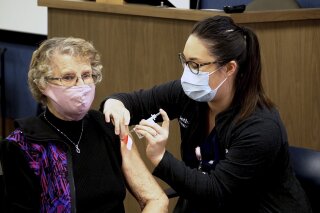 Corrine Bakken, 93, of West Fargo, becomes the first patient of the state’s largest private hospital, Sanford Health, to receive the COVID-10 vaccine on Thursday, Jan. 14, 2021, in Fargo, N.D. The coronavirus forced Bakken to retire from her job as a special needs paraprofessional and says she wants to be vaccinated to see her children, grandchildren and great-grandchildren. After the shot she said, “Now I can live to be 100.” (AP Photo/Sanford Health)