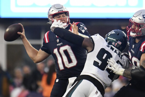 New England Patriots quarterback Mac Jones (10) looks to pass under pressure from Philadelphia Eagles defensive end Josh Sweat (94) in the second half of an NFL football game, Sunday, Sept. 10, 2023, in Foxborough, Mass. (AP Photo/Mark Stockwell)