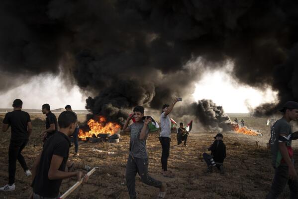 FILE - Palestinians burn tires during a protest against Israeli military raid in the West Bank, along the border fence with Israel, in east of Gaza City on Oct. 25, 2022. The U.N. Mideast envoy said 2022 is on course to be the deadliest year for Palestinians in the West Bank since the U.N. started tracking fatalities in 2005, and he called for immediate action to calm "an explosive situation" and move toward renewing Israeli-Palestinian negotiations. (AP Photo/Fatima Shbair, File)