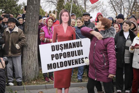 FILE - A woman slaps a cardboard cutout of Moldova's pro-western President Maia Sandu, with writing reading "Enemy of the Moldovan People", during a protest initiated by the populist Shor Party, in Chisinau, Moldova, Sunday, Nov. 13, 2022. Shor, a fugitive Moldovan oligarch and opposition leader has been sentenced in absentia to 15 years in jail for his alleged role in a one-billion-dollar bank fraud case, Moldova's President said. The Court of Appeal in the capital, Chisinau, sentenced Ilan Shor, who leads the populist Russia-friendly Shor Party, on charges of fraud and money laundering on Thursday, April 13, 2023. (AP Photo/Vadim Ghirda, File)