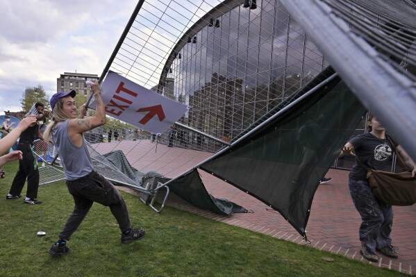 Protesters tear down a barricade set up outside the pro-Palestinian campus of the Massachusetts Institute of Technology on Monday, May 6, 2024, in Cambridge, Massachusetts. Hundreds of demonstrators crossed the barricades and joined pro-Palestinian demonstrators who had been given permission. Deadline for leaving camp.  (AP Photo/Josh Reynolds)