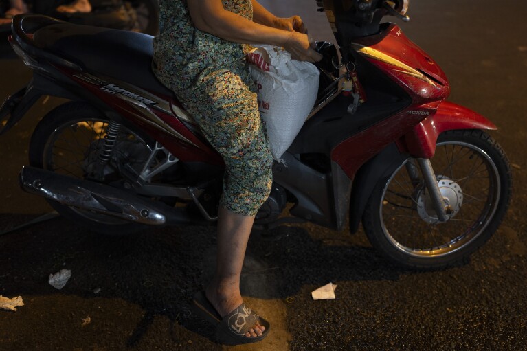 2024 年 1 月 24 日星期三，一名妇女坐在摩托车上，手里拿着一袋从越南胡志明市当地市场购买的大米。越南是世界第三大大米出口国，越南文化的主要重要性是显而易见的在湄公河三角洲。  （美联社照片/Jae C. Hong）