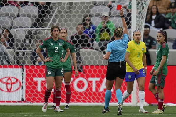 Mexico's Nicolette Hernandez, right, is shown a red card by referee Tori Penso during the first half of a CONCACAF Gold Cup women's soccer tournament semifinal match against Brazil, Wednesday, March 6, 2024, in San Diego. (AP Photo/Gregory Bull)