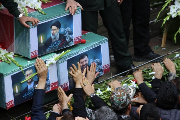 In this photo provided by Fars News Agency، mourners try to touch the coffins of Iranian President Ebrahim Raisi، top، Foreign Minister Hossein Amirabdollahian، left، and Raisi's chief bodyguard Gen. Mehdi Mousavi، who were killed in a helicopter crash on Sunday in a mountainous region of the country's northwest، during a funeral ceremony at the city of Tabriz، Iran، Tuesday، May 21، 2024. Mourners in black began gathering Tuesday for days of funerals and processions for Iran's late president، foreign minister and others killed in a helicopter crash، a government-led series of ceremonies aimed at both honoring the dead and projecting strength in an unsettled Middle East. (Ata Dadashi، Fars News Agency via AP)