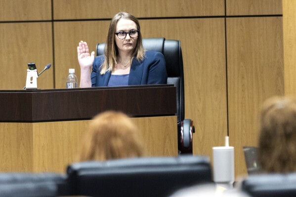 FILE - Cobb County teacher Katie Rinderle is sworn in to testify during a hearing at the Cobb County Board of Education in Marietta, Ga., Aug. 10, 2023. The firing of Rinderle, a Georgia teacher who read a book on gender fluidity to her fifth grade class, was upheld Thursday, Feb. 22, 2024, by the Georgia Board of Education. (Arvin Temkar/Atlanta Journal-Constitution via AP, File)