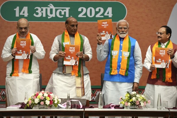 Indian Prime Minister Narendra Modi, second right, releases his ruling Bharatiya Janata Party's manifesto for the upcoming national parliamentary elections in New Delhi, India, Sunday, April 14, 2024. Standing from L to R with him are BJP's senior leaders Home Minister Amit Shah, Defence Minister Rajnath Singh and Party President JP Nadda. (AP Photo/Manish Swarup)