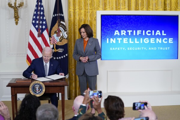 President Joe Biden signs an executive on artificial intelligence in the East Room of the White House, Monday, Oct. 30, 2023, in Washington. Vice President Kamala Harris looks on at right. (AP Photo/Evan Vucci)