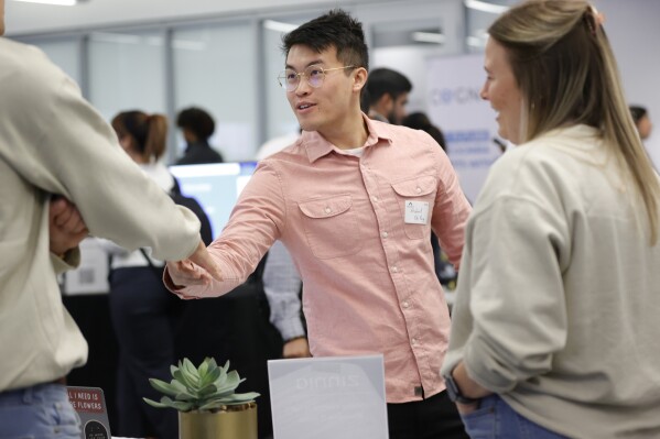 Georgia Tech student Michael Oh-Yang, center, greets company representatives during the Startup Student Connection job fair, Wednesday, March 29, 2023, in Atlanta. For the thousands of workers who'd never experienced upheaval in the tech sector, the recent mass layoffs at companies like Google, Microsoft, Amazon and Meta came as a shock. Now they are being courted by long-established employers whose names aren't typically synonymous with tech work, including hotel chains, retailers, investment firms, railroad companies and even the Internal Revenue Service.(AP Photo/Alex Sliz)