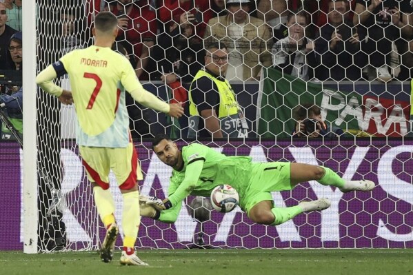 Portugal goalkeeper Diogo Costa makes a save against Spain's Alvaro Morata in the penalty shootout of the Nations League final soccer match between Portugal and Spain at the Allianz Arena in Munich, Germany, Sunday, June 8, 2025. (Christian Charisius, dpa via AP)