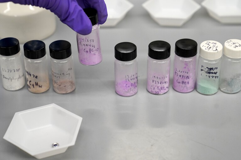 Dan Laorenza, of North Andover, Mass., a post-doctoral researcher at Harvard University, places a vile of cobalt-based hybrid material among other hybrid materials being evaluated as candidates for solid refrigerants, in a lab on the school's campus, Thursday, Sept. 14, 2023, in Cambridge, Mass. The mixtures are part of research to develop a more environmentally-friendly solid refrigerant that could be used as an alternative to existing volatile refrigerants. (AP Photo/Steven Senne)