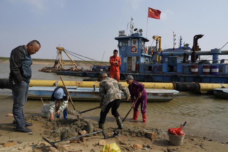 Residents using shovels and metal detector to search for antique coins and metal parts as the bed of Poyang Lake is accessible during drought season in north-central China's Jiangxi province on Tuesday, Nov. 1, 2022. A prolonged drought since July has dramatically shrunk China’s biggest freshwater lake, Poyang. (AP Photo/Ng Han Guan)
