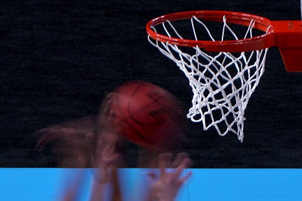 In this photo taken with a slow shutter, players compete for a rebound during the first half of a college basketball game between UConn and Syracuse in the second round of the women's NCAA tournament at the Alamodome in San Antonio, Tuesday, March 23, 2021. (AP Photo/Charlie Riedel)