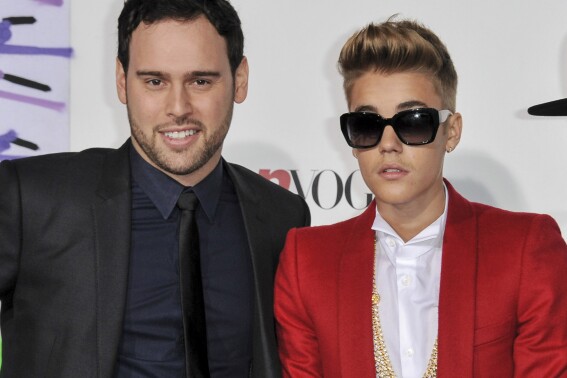FILE - Music executive Scooter Braun, left, appears with Justin Bieber at the World Premiere of "Justin Bieber's Believe" in Los Angeles on Dec. 18, 2013. Braun is one of the most recognizable names in the music business for his work as an executive, entrepreneur, and artist manager. Publicly, he's best known for two things: discovering Justin Bieber and purchasing the master recordings to Taylor Swift's first six album, inspiring her to re-record them in an ongoing series called “Taylor's Version.” (Photo by Richard Shotwell/Invision/AP, File)