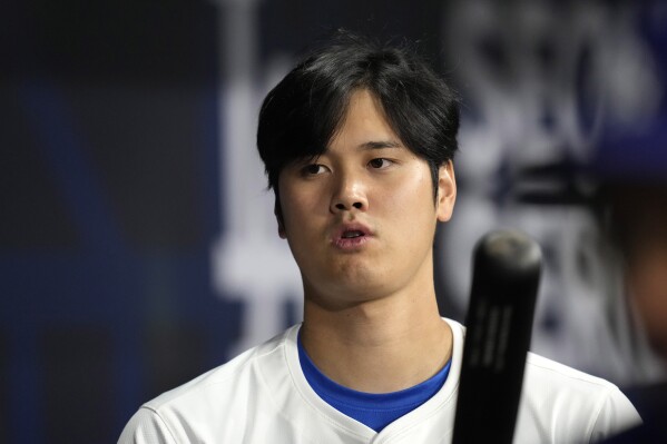 Los Angeles Dodgers designated hitter Shohei Ohtani stands in the dugout during the first inning of a baseball game against the San Diego Padres at the Gocheok Sky Dome in Seoul, South Korea Thursday, March 21, 2024, in Seoul, South Korea. (AP Photo/Lee Jin-man)