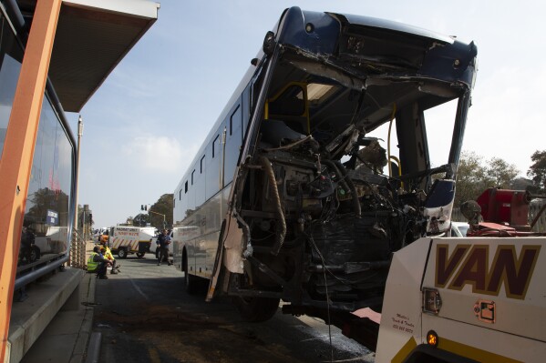 A bus is towed away after being involved in a collision at the entrance to a university in Johannesburg, Tuesday, July 25, 2023. At least 77 people were injured, five of them critically, after two buses collided at the entrance to a South African university on Tuesday, police and transport authorities said. (AP Photo/Denis Farrell)
