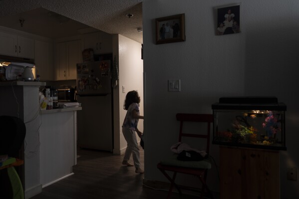 Rubie Caceres, a granddaughter of Marina Maalouf, a longtime resident of Hillside Villa who participated in protests after rents doubled in 2019, enters a bedroom in her apartment in Los Angeles, Tuesday, Oct. 1, 2024. (AP Photo/Jae C. Hong)