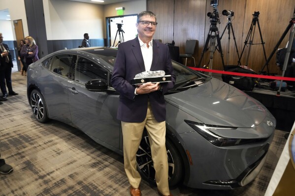 Scott Neiheisel, Toyota North America, stands with the Toyota Prius winning the 2024 North American Car of the Year award, Thursday, Jan. 4, 2024, in Pontiac, Mich. (AP Photo/Paul Sancya)