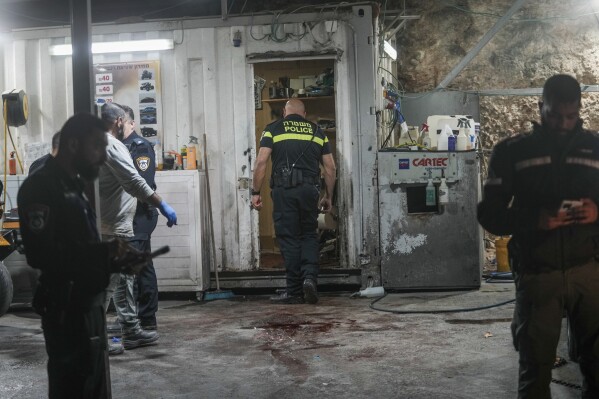 Israeli police examine the crime scene where a gunman opened fire at a car wash in Yafa an-Naseriyye, near Nazareth, Israel, Thursday, June 8, 2023. Five people were killed in the shooting, the latest in a wave of criminal violence tearing through the country's Palestinian communities. More than 100 people have been killed in violent crime in Arab communities since the start of this year, more than three times higher than at the same time last year. (AP Photo/Mahmoud Illean)