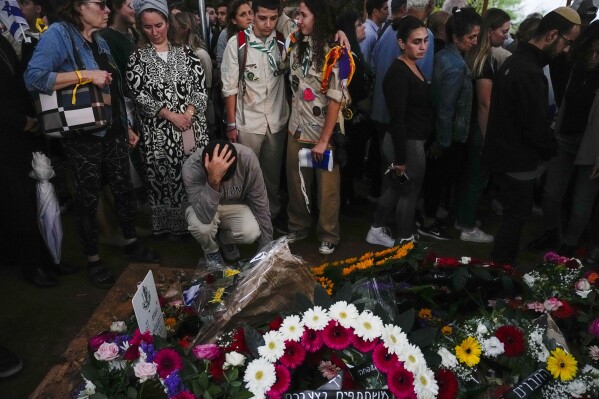 Mourners gather around the grave of Israeli reserve soldier Master sergeant Raz Abulafia at the end of his funeral in the village of Rishpon, Israel, Tuesday, Nov. 14, 2023. Abulafia, 27, was killed during a military ground operation in the Gaza Strip. (AP Photo/Ariel Schalit)