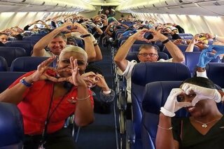 This Friday, March 27, 2020, photo provided by Southwest Airlines employee Dayartra Etheridge shows health care workers, other passengers and flight crew aboard a Southwest flight from Atlanta to New York's LaGuardia Airport holding their hands in the shape of a heart, before the plane pushed back from the gate, at Hartsfield-Jackson Atlanta International Airport. There were about 30 health care professionals, all from Atlanta-area hospitals, who were on the regularly scheduled flight to LaGuardia, to help with the coronavirus outbreak in New York. (Dayartra Etheridge via AP)