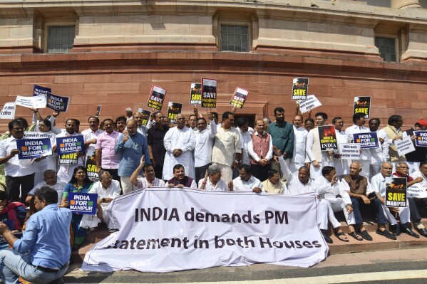 FILE - Opposition lawmakers demanding a statement from Prime Minister Narendra Modi on the violence in Manipur state carry placards and a banner with name of "INDIA" outside the Parliament building in New Delhi, India, Monday, July 24, 2023. India’s fractured opposition parties have joined forces in a rare show of unity and formed an alliance called 'INDIA' to unseat the popular but polarizing prime minister Narendra Modi and his Hindu nationalist Bharatiya Janata Party. Last week, more than two dozen parties joined the alliance, named the Indian National Developmental Inclusive Alliance which is called INDIA for short. (AP Photo, File)