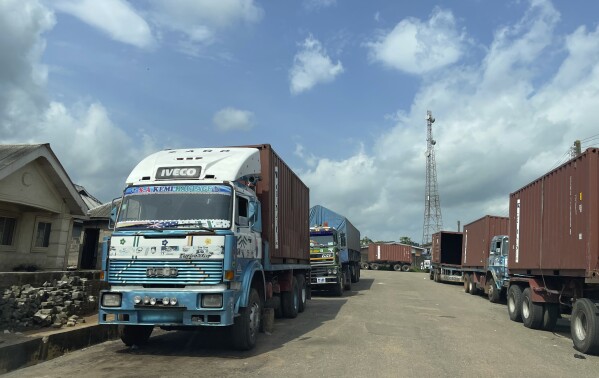 Trucks are parked outside the Tulip Cocoa Processing Ltd factory in Ijebu-Imushin, Nigeria, Monday, Oct. 23, 2023. Farmers, buyers and others say cocoa heads from deforested areas of the protected reserve to companies that supply some of the world’s biggest chocolate makers.(AP Photo/Sunday Alamba)