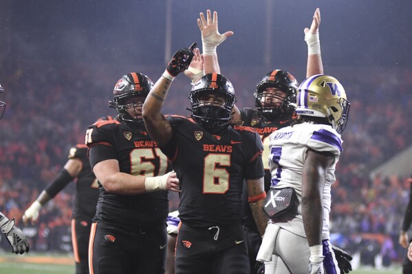 Oregon State running back Damien Martinez, center, celebrates his touchdown with offensive linemen Tanner Miller, left, and Jake Levengood, while Washington cornerback Dominique Hampton, right, walks away during the second half of an NCAA college football game Saturday, Nov. 18, 2023, in Corvallis, Ore. (AP Photo/Mark Ylen)