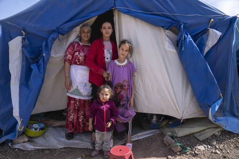 A family displaced by the September earthquake poses for a photograph outside their tent, in Moulay Brahim, outside Marrakech, Morocco, Saturday, Oct. 7, 2023. (AP Photo/Mosa'ab Elshamy)
