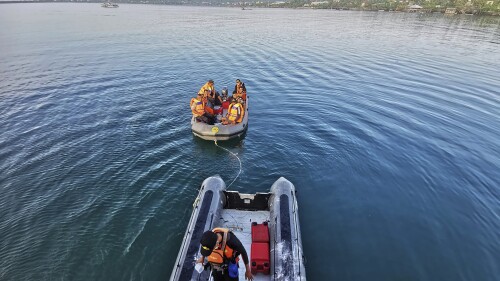 In this photo provided by the National Search and Rescue Agency (BASARNAS), rescuers on a rubber boat search for survivors after an overloaded ferry sank off Sulawesi Island, Indonesia, Monday, July 24, 2023. (BASARNAS via AP)