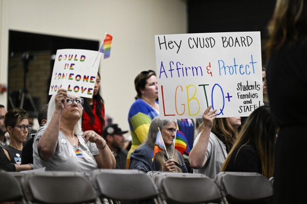 FILE - Parents, students, and staff of Chino Valley Unified School District hold up signs in favor of protecting LGBTQ+ policies at Don Antonio Lugo High School, on June 15, 2023, in Chino, Calif. The school district approved changes on Thursday, March 7, 2024, to a policy that required school staff to notify parents if their child asks to change pronouns at school. The updated policy passed by the board removes mentions of student gender identification changes. (Anjali Sharif-Paul/The Orange County Register via AP, File)