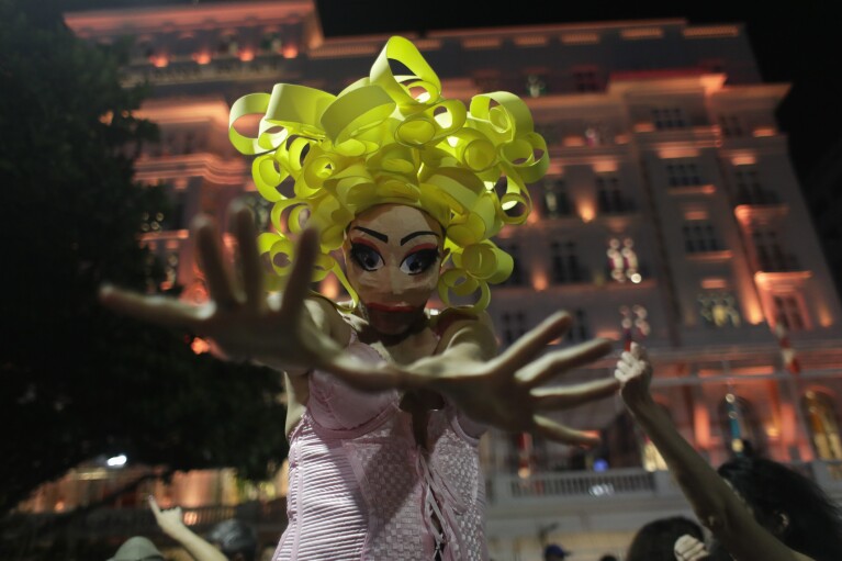 A Madonna fan, wearing a mask, strikes a pose during rehearsal for Madonna's The Celebration Tour, in Rio de Janeiro, Brazil, Thursday, May 2, 2024. Madonna will conclude her tour on Saturday with a free concert on Copacabana Beach.  (AP Photo/Bruna Prado)