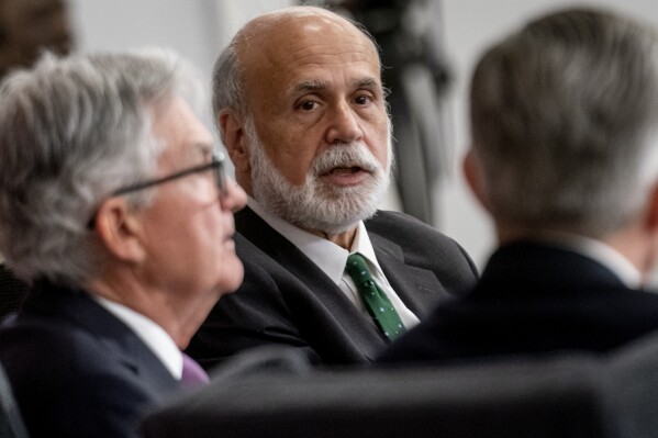 FILE - Former Federal Reserve Chairman Ben Bernanke, center, accompanied by Federal Reserve Chairman Jerome Powell, left, speaks during the Thomas Laubach Research Conference at the William McChesney Martin Jr. Federal Reserve Board Building in Washington, on May 19, 2023. A review of the Bank of England's economic forecasting that was published Friday April 12, 2024 and undertaken by Ben Bernanke, the former chair of the U.S. Federal Reserve, has found “significant shortcomings” that should be addressed to better inform future interest rate decisions. (AP Photo/Andrew Harnik, File)