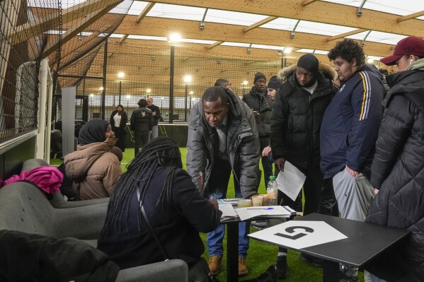 Job seekers line up to get the application papers during the Olympics jobs fair at sport center in Paris, Thursday, Dec. 14, 2023. Organizers urgently need many thousands of recruits for the huge security operation that will aim to keep athletes and spectators safe during the July 26-Aug. 11 Summer Games in the French capital that has been repeatedly hit by deadly extremist attacks. (AP Photo/Michel Euler)