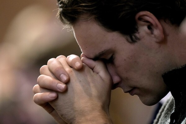 A man prays during Catholic Mass at Benedictine College Sunday, Oct. 29, 2023, in Atchison, Kan. Many Catholic parishes are becoming more conservative as they move away from modernizing reforms that swept the church more than 50 years ago. (AP Photo/Charlie Riedel)