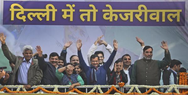 Incumbent Delhi Chief Minister Arvind Kejriwal, center, along with family members and supporters wave at Aam Aadmi Party, or "common man's" party headquarters as they celebrate the party's victory in New Delhi, India, Tuesday, Feb. 11, 2020. Indian Prime Minister Narendra Modi's Hindu nationalist party was facing a stunning defeat by a regional party Tuesday in elections in the national capital that were seen as a referendum on Modi's policies such as a new national citizenship law that excludes Muslims. Banner in Hindi reads, "In Delhi, its Kejriwal". (AP Photo/Manish Swarup)